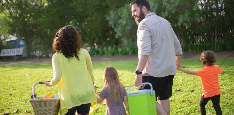 A family of four enjoys a picnic in a sunny park, capturing a joyful day outdoors.